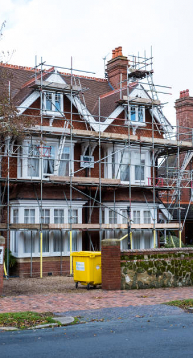 East Dean, England - Sept 10, 2020: Traditional semi-detached house undergoing renovation with scaffolding and boards around the housel - street view.
